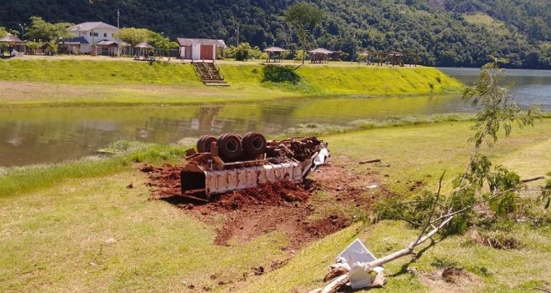 Caminhão caçamba desgovernado capota próximo a rio